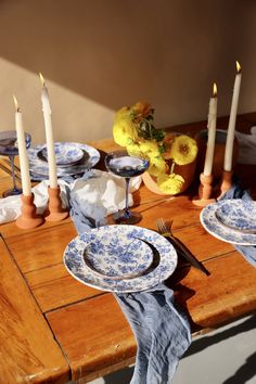 the table is set with blue and white china plates, candles, and flowers in vases