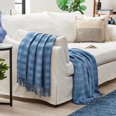 a living room with a white couch and blue throw blanket on the back of it