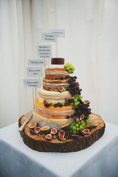 a wedding cake with figurines, grapes and cheese on the top tiers