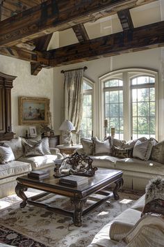 a living room filled with lots of furniture next to two large windows on top of a wooden ceiling