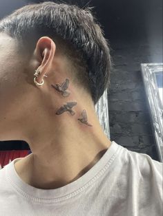 a man with a small bird tattoo on his left side of the neck and behind his ear