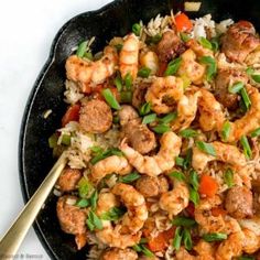 a skillet filled with shrimp, rice and veggies on top of a table