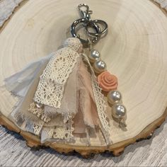 a keychain with beads and lace on it sitting on top of a piece of wood