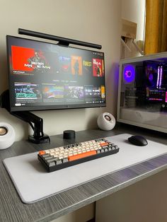 a desk with a keyboard, monitor and speakers on it in front of a television