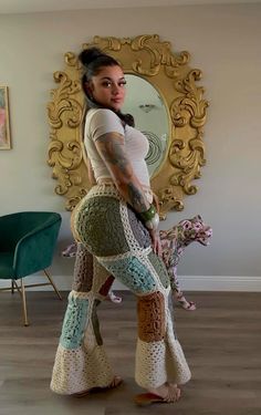 a woman standing in front of a mirror wearing crocheted pants and sandals with her legs crossed