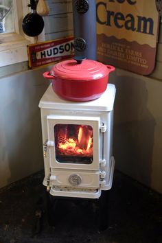 an old fashioned stove with a red pot on top