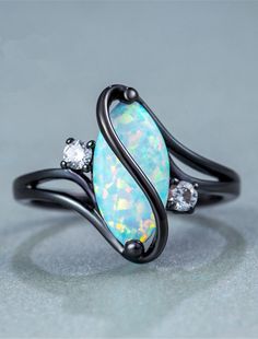 an opalite and diamond ring with black metal band, on a gray surface