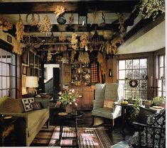 a living room filled with furniture and lots of plants hanging from the ceiling next to windows