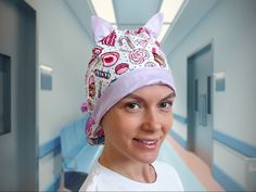 a woman wearing a cat hat and smiling for the camera in a hospital hallway with blue walls