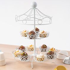 a three tiered cupcake stand on top of a wooden table