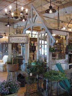 the inside of a store with lots of potted plants and lights hanging from the ceiling