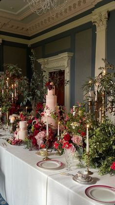 the table is set up with pink and red flowers, candles, and cake on it