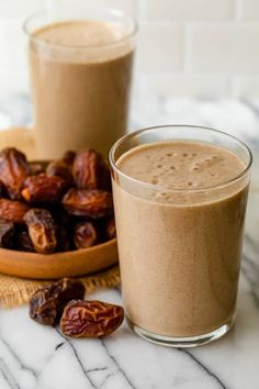 two glasses filled with smoothie next to some nuts