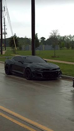 a black sports car is parked in the rain