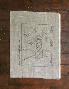 a piece of linen with a lighthouse on it sitting on top of a wooden floor