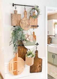 a kitchen wall with cutting boards hanging from it's sides and potted plants on the hooks