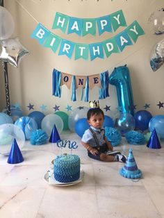 a little boy sitting in front of a birthday cake