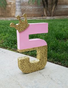 the letter e is made out of gold glitter and has a princess crown on it