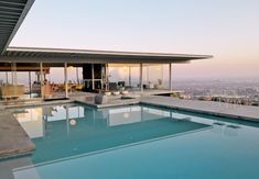 an outdoor swimming pool in front of a large building with a view of the city