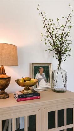 there is a vase with some flowers on the table next to books and a lamp