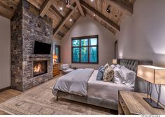 a bedroom with a stone fireplace and large bed