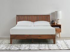 a wooden bed frame with white sheets and pillows