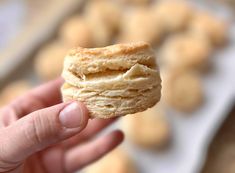 a hand holding a half eaten biscuit in front of some cookies