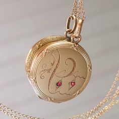 "Sweet romantic locket from the Art Nouveau/Jugendstil era. Fine hand engraved pattern at the front with two ruby paste stones. Ornate relief frame going all around, with little bows. The back is plain. Details: The locket is from the Art Nouveau era, early 20th century. It is stamped \"FIX\" at the bale, which stands for a high quality 18k gold plating popular in France at Victorian times. Condition: It is in very good antique condition. Some light surface wear, scratches and a nice patina to the outside. There is no dent that I can see. Inside there is some oxidation, please inspect the photos. The two original rings are present, reasy to hold your photos. It closes tightly with a snap. The locket is sold with a new 18\" gold filled chain that is stamped 1/20 14k at the clasp. Measuremen Antique Engraved Red Jewelry, Red Engraved Antique Jewelry, Red Victorian Engraved Jewelry, Formal Compact Locket Jewelry, Victorian Locket Jewelry, Antique Compact Locket Jewelry, Victorian Compact Locket Jewelry, Victorian Red Medallion Jewelry, Red Victorian Medallion Jewelry