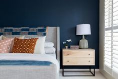 a bedroom with blue walls, white bedding and two nightstands next to each other