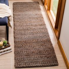 a brown rug sitting on top of a floor next to a blue chair and window