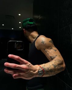 a man with tattoos on his arm taking a selfie in front of a mirror