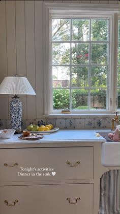 there is a sink in the kitchen next to a window with a lamp on it