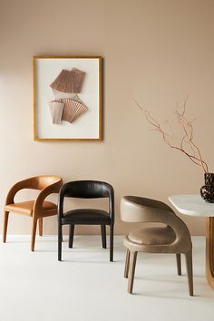 three chairs and a table in a room with a painting on the wall behind them