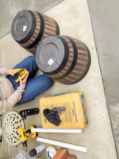 a woman sitting on the ground with tools and equipment around her, including drillers