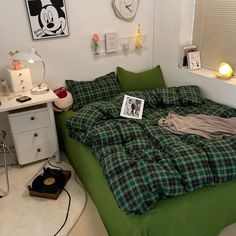 a bedroom with a green bed and mickey mouse pictures on the wall