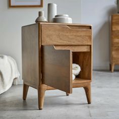 a small wooden cabinet sitting on top of a floor next to a white bed and dresser