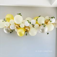 a bunch of balloons that are hanging from the ceiling in front of a white wall