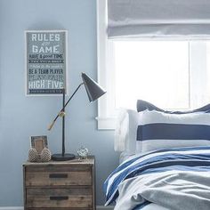 a bedroom with blue walls and striped bedding, two nightstands on either side