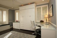 a white desk and chair in a room with shutters on the window sill