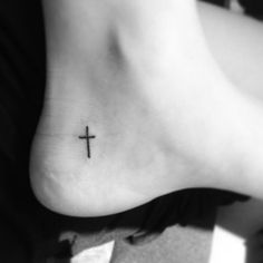 a small cross tattoo on the side of a woman's lower body and foot