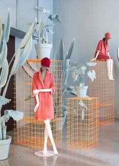 three mannequins dressed in pink and white are standing next to some plants