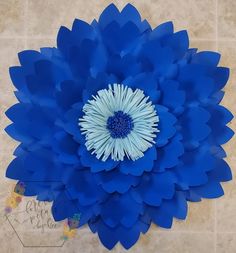 a large blue flower sitting on top of a tile floor