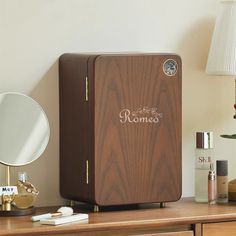 a wooden box sitting on top of a desk next to a mirror and lamp with the word romance written on it