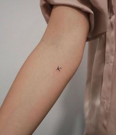 a small airplane tattoo on the left inner arm, which is black and white in color