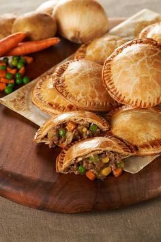 several pastries on a wooden plate with carrots and peas