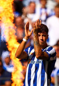 a soccer player holding his hands up in the air with flames coming from behind him