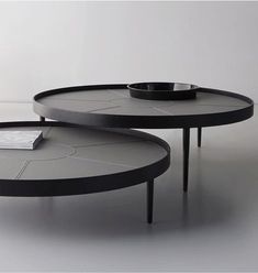 two round tables with black bases on each side and a book on the table top