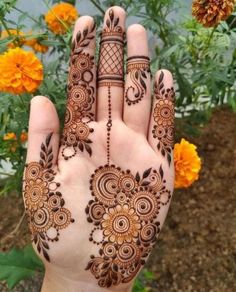 a woman's hand with henna tattoos on it and flowers in the background