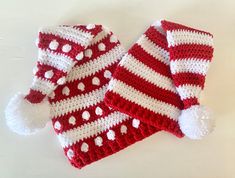 two red and white crocheted hats with pom - poms on them