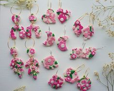 some pink flowers and green leaves are on the table next to other items that have been made out of clay